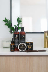 Full Beard Grooming Kit featuring beard oil, balm, wash, conditioner, and accessories on a bathroom countertop.