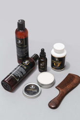 Full Beard Grooming Kit with beard wash, oil, balm, supplement, and wooden comb on a gray background.