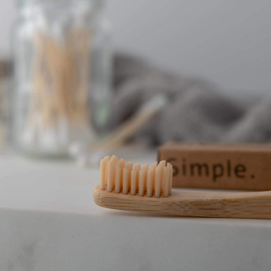 Bamboo toothbrush with medium wavy bristles, promoting eco-friendly dental care in a minimalist setting.