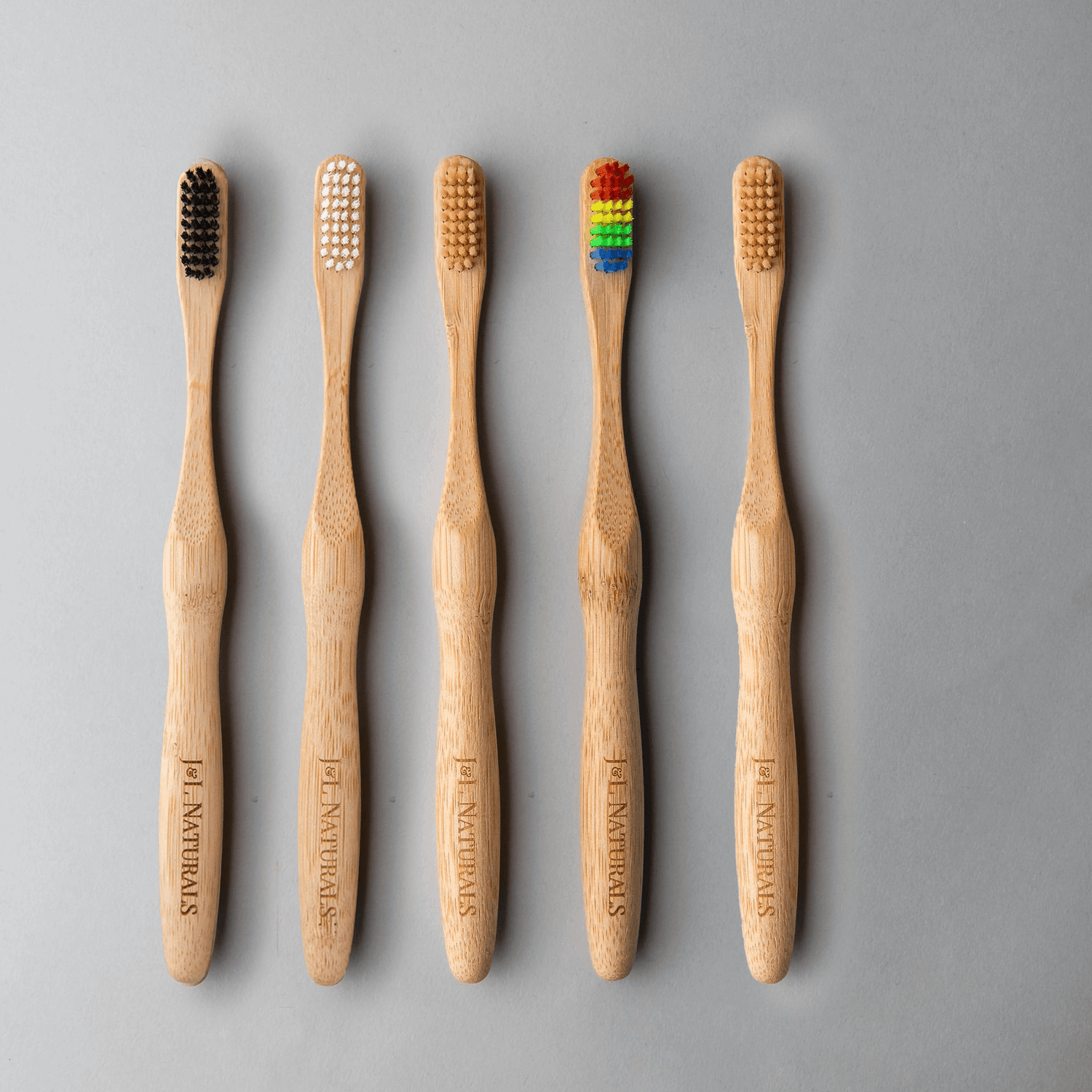 Bamboo toothbrush bundle showing five eco-friendly brushes with varied bristle colors on a light grey background.