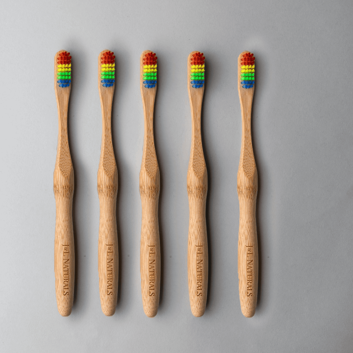 Bamboo toothbrush bundle featuring five eco-friendly brushes with colorful bristles on a gray background.