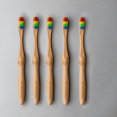 Bamboo toothbrush bundle featuring five eco-friendly brushes with colorful bristles on a gray background.