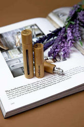 Two bamboo roll-on bottles with essential oils on an open book with lavender sprigs, perfect for women&