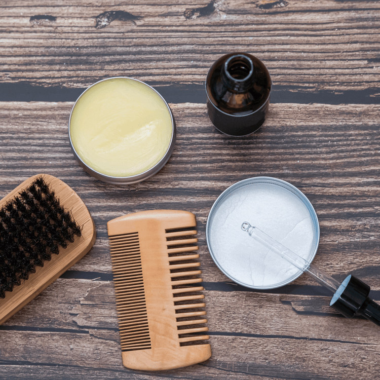 Full Beard Grooming Kit with beard oil, balm, brush, and comb on wooden table.