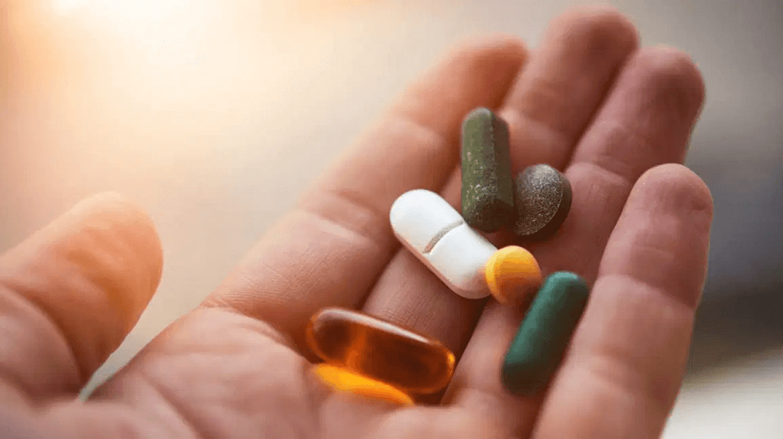 Hand holding various dietary supplements and vitamins, emphasizing natural weight loss solutions.