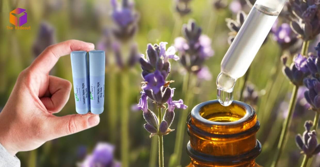 Hand holding headache essential oil rollers with lavender flowers and dropper bottle in background.