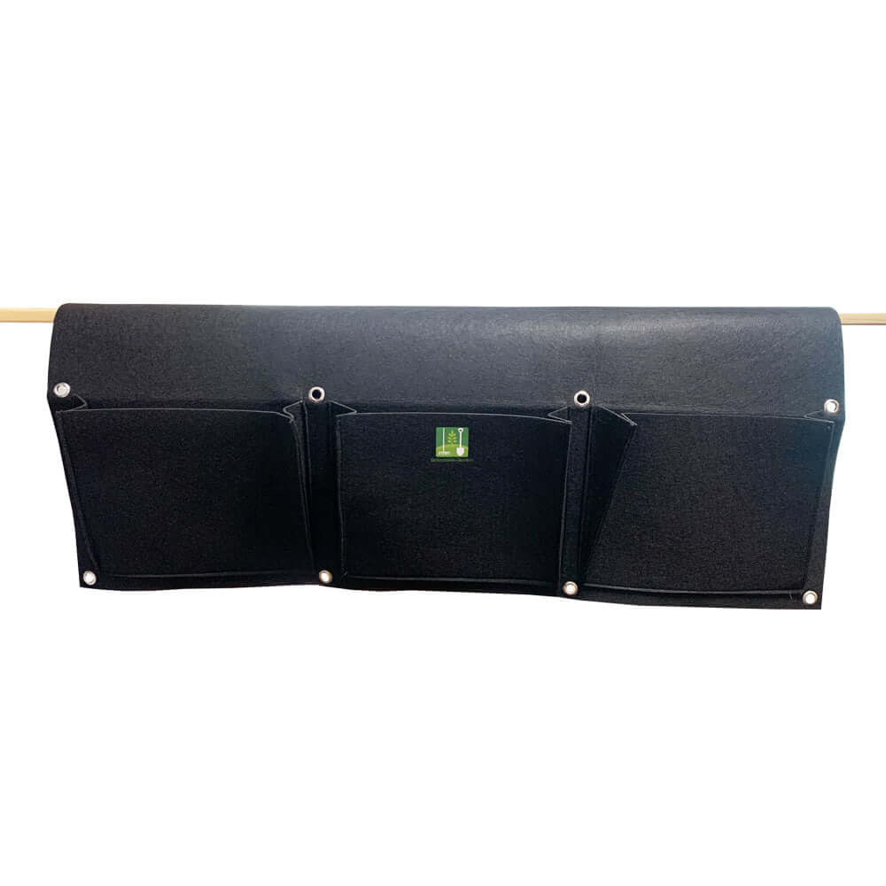Black cloth saddlebag planter with six pockets for hanging on a fence or balcony, perfect for flowers and herbs.