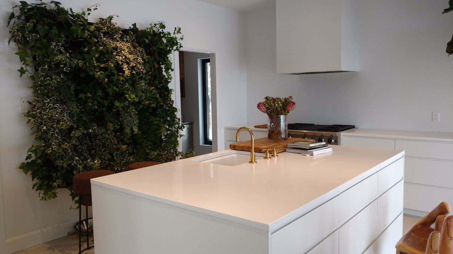 Indoor kitchen featuring a stylish vertical living wall planter with lush greenery against a modern white backdrop.