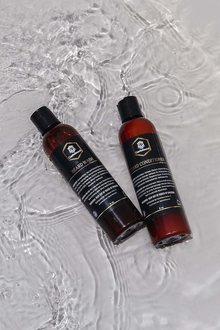 Beard wash and conditioner set bottles on wet surface, designed for cleaning and conditioning beards without stripping oils.
