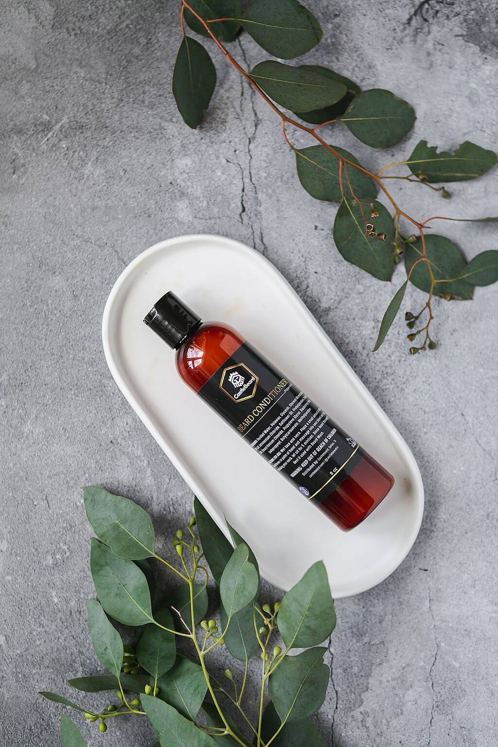 Beard wash bottle displayed on a tray with greenery, highlighting its cleansing and conditioning properties for men.