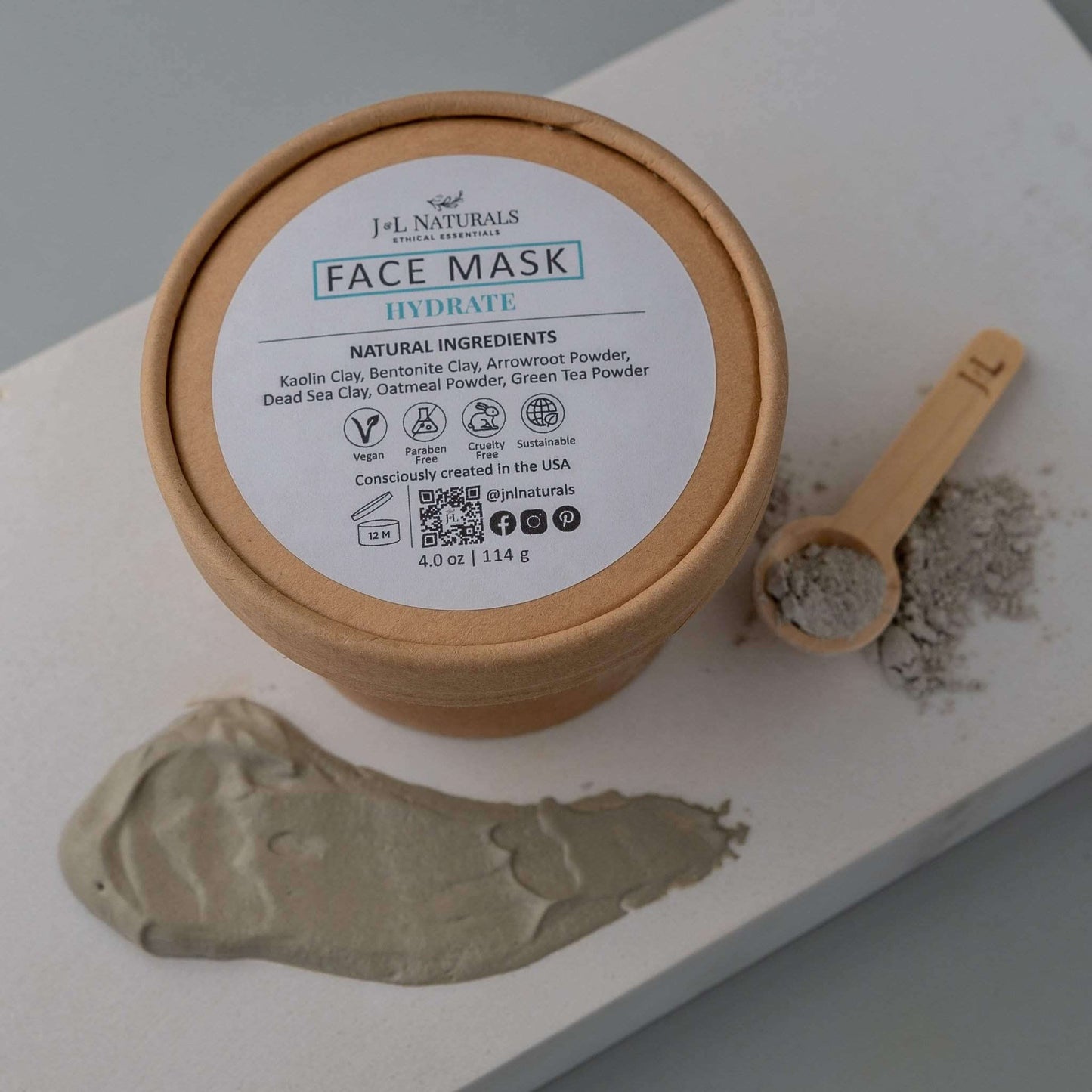 Hydrating face mask by J-L Naturals with natural ingredients, clay, and a measuring spoon on a surface.