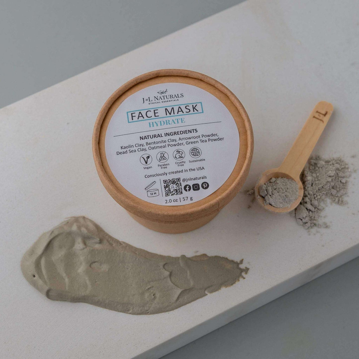 Hydrating face mask in eco-friendly packaging with natural ingredients displayed on a marble surface.