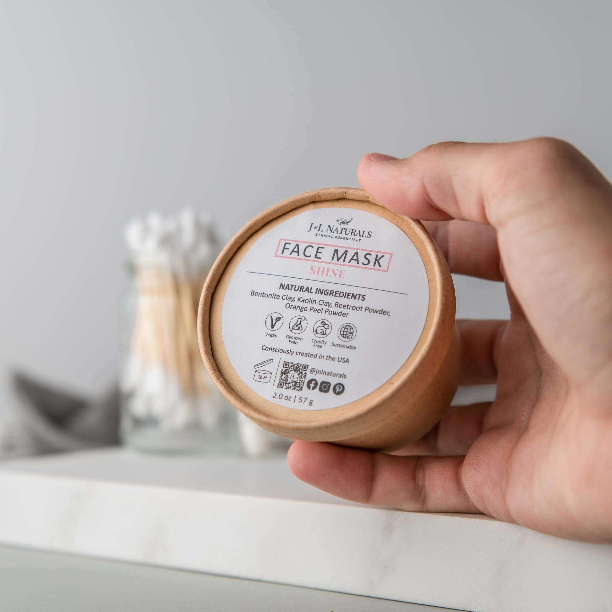 Hand holding a jar of natural face mask, labeled 'Face Mask Shine', showcasing clean ingredients.