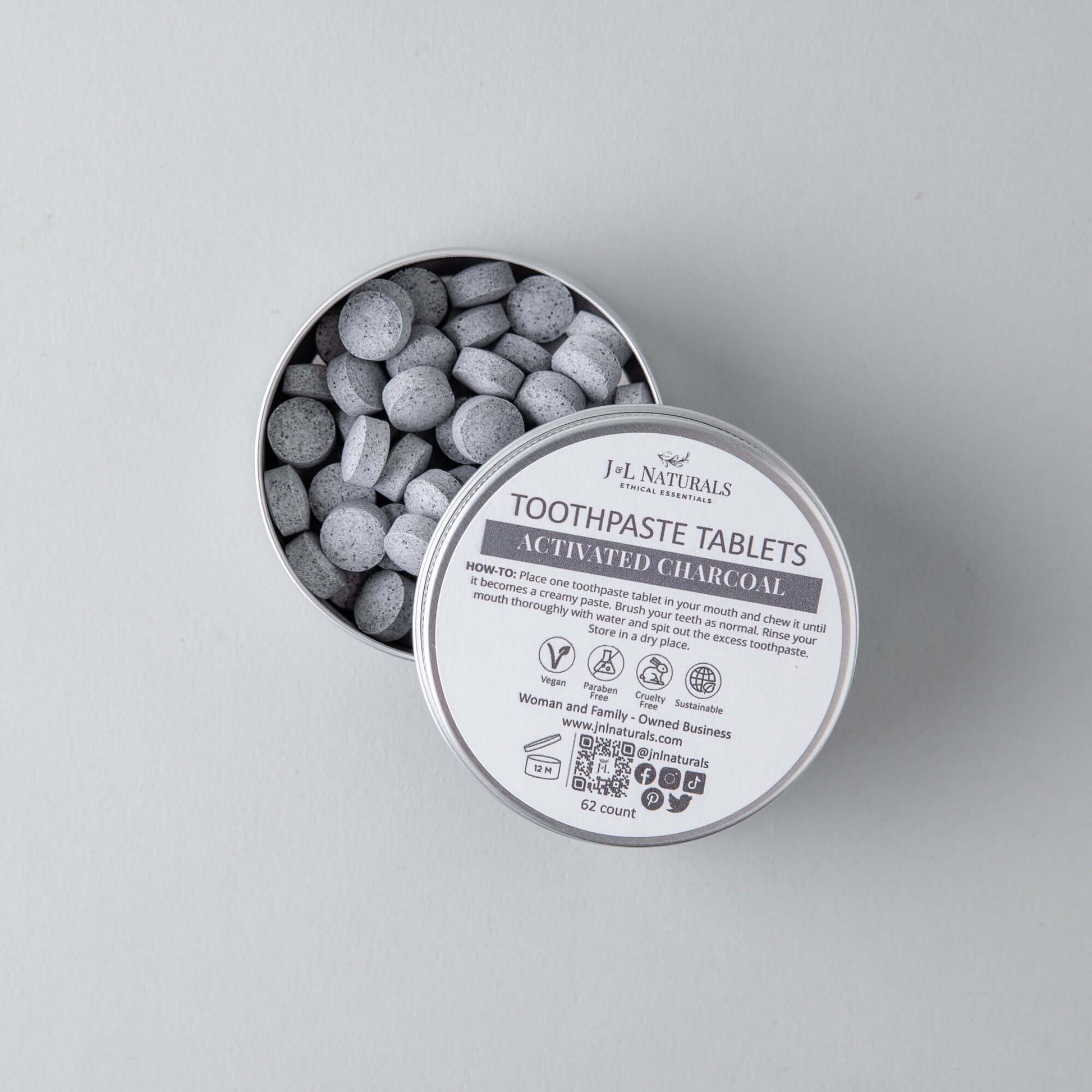 Eco-friendly toothpaste tablets in a tin, featuring activated charcoal for fresh dental hygiene.