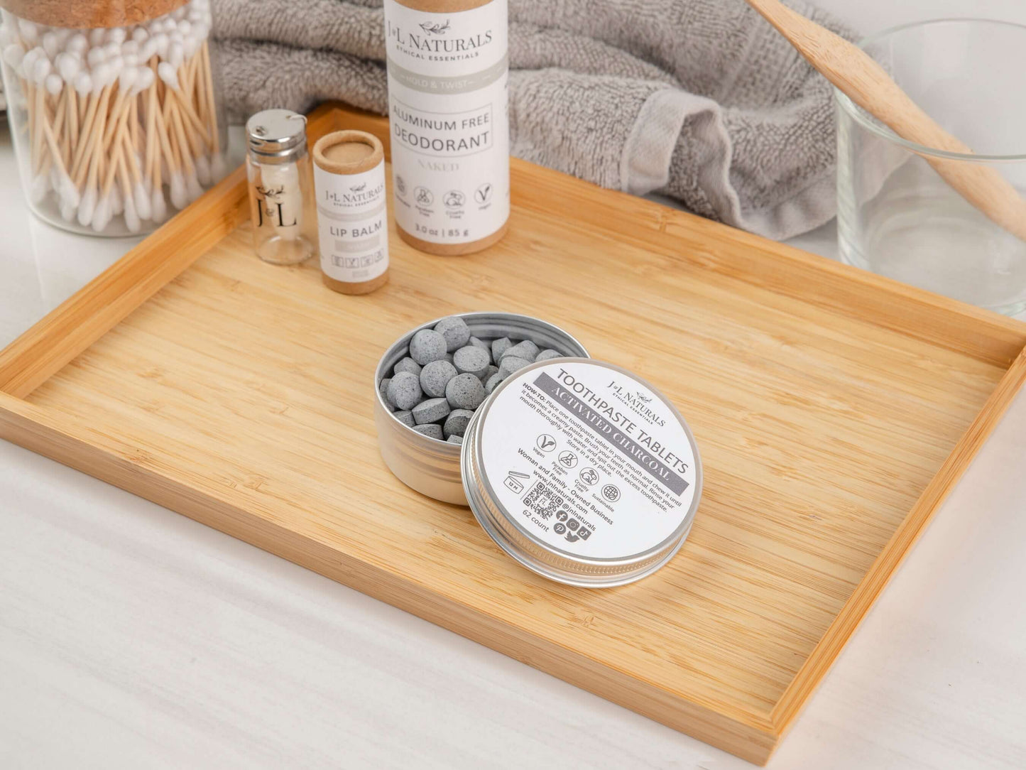 Eco-friendly toothpaste tablets in a metal tin on a bamboo tray, promoting sustainable dental hygiene.