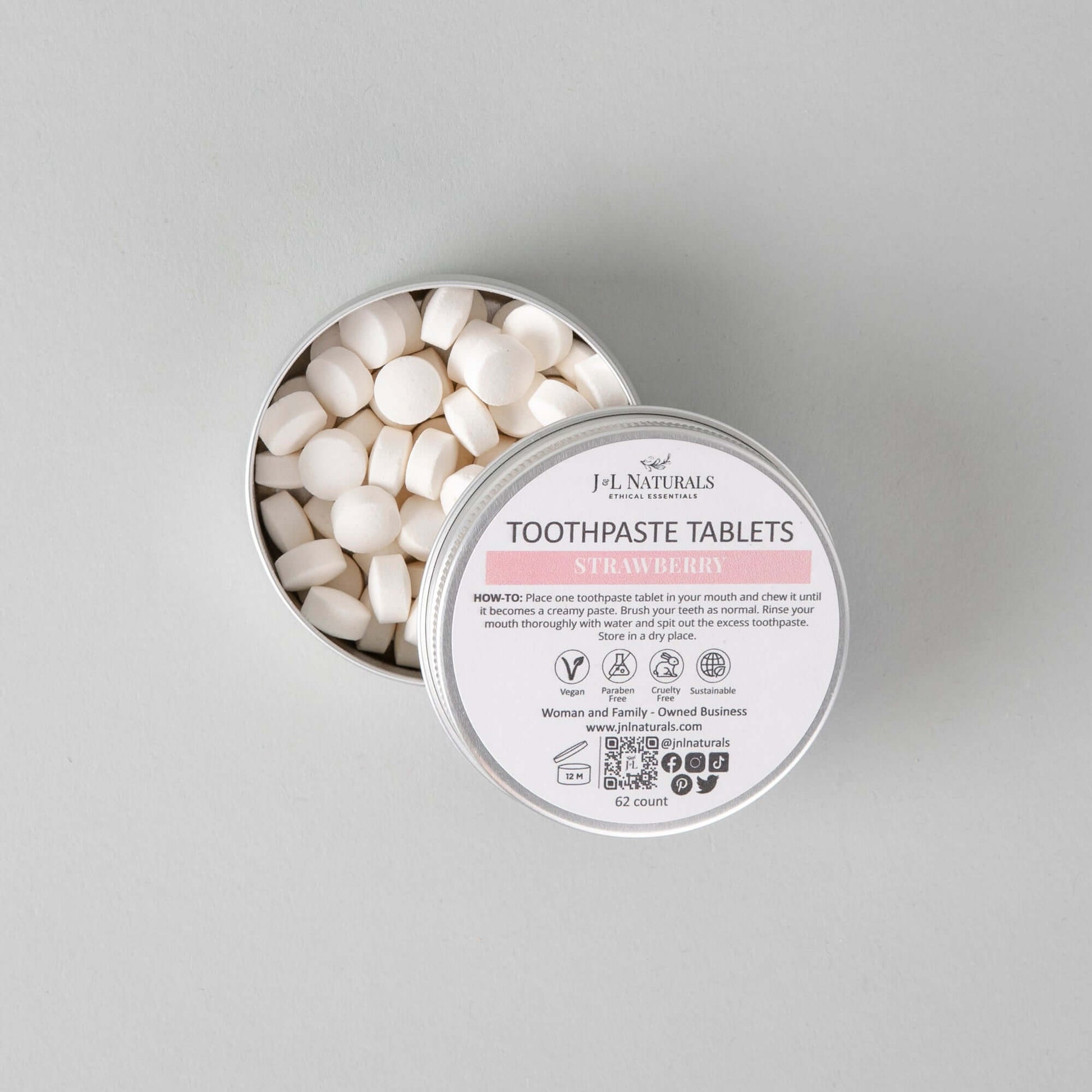 Eco-friendly toothpaste tablets in a tin, featuring all-natural ingredients and strawberry flavor for fresh dental care.