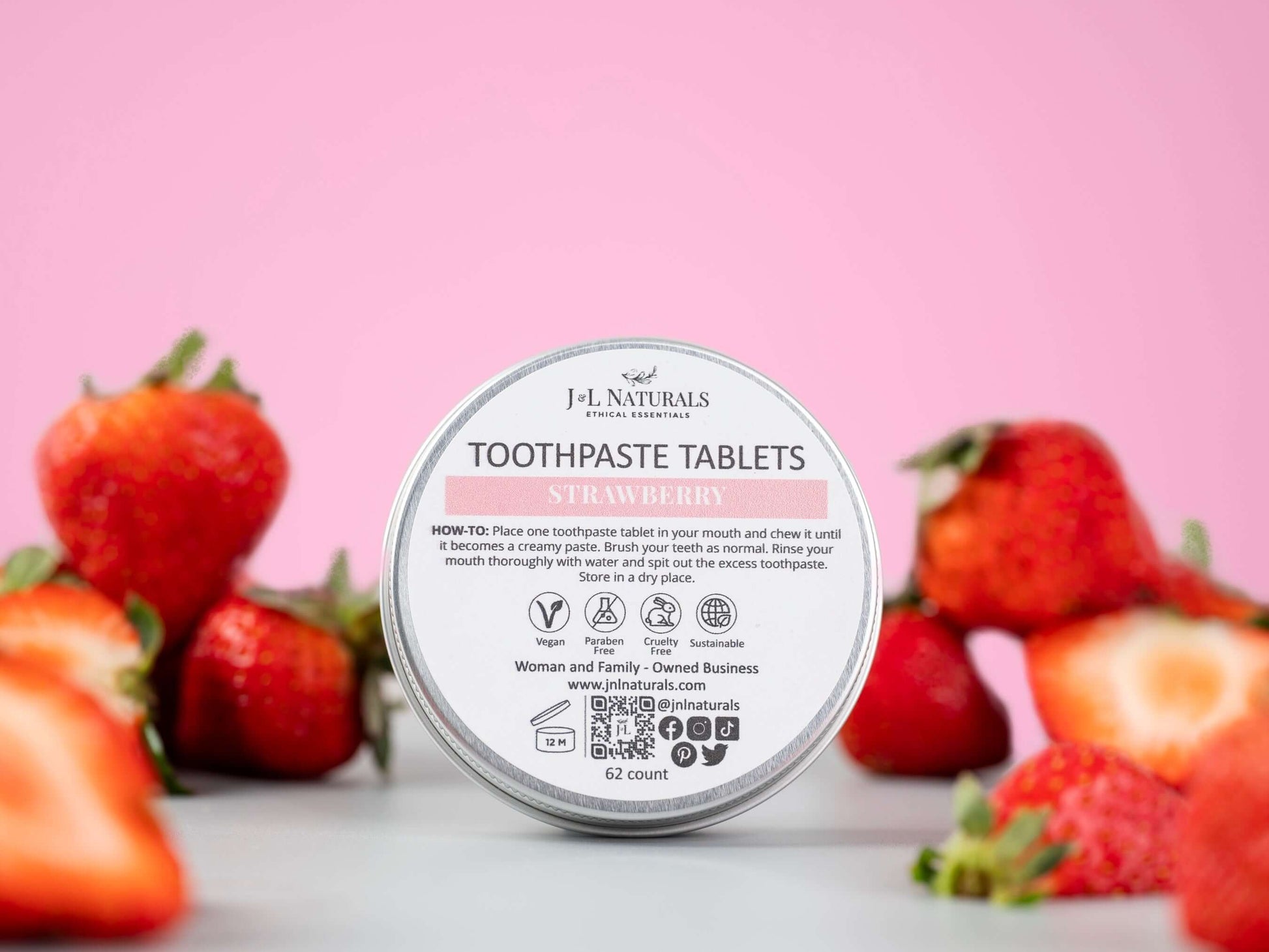 Strawberry-flavored all-natural toothpaste tablets in eco-friendly packaging, surrounded by fresh strawberries.