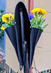 Cloth 6 pocket saddlebag planter with flowers, hanging on a fence for vertical gardening.