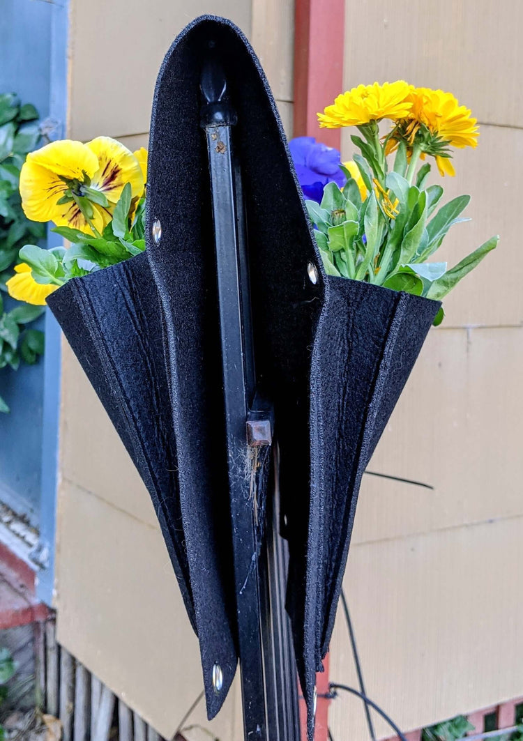 Cloth 6 pocket saddlebag planter with flowers, hanging on a fence for vertical gardening.
