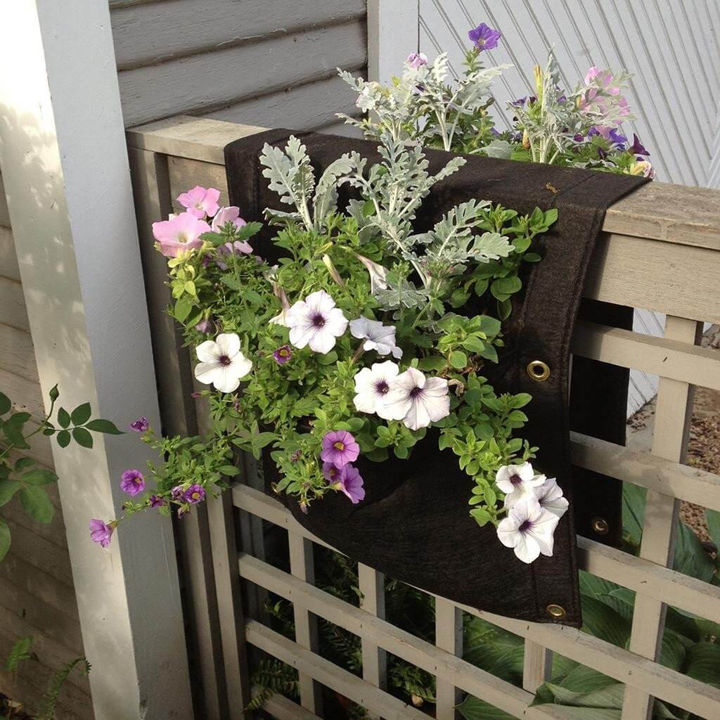 Eco-friendly urban saddlebag planter with colorful flowers hanging over a fence.