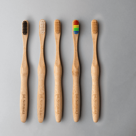 Bamboo toothbrush bundle showing five eco-friendly brushes with varied bristle colors on a light grey background.