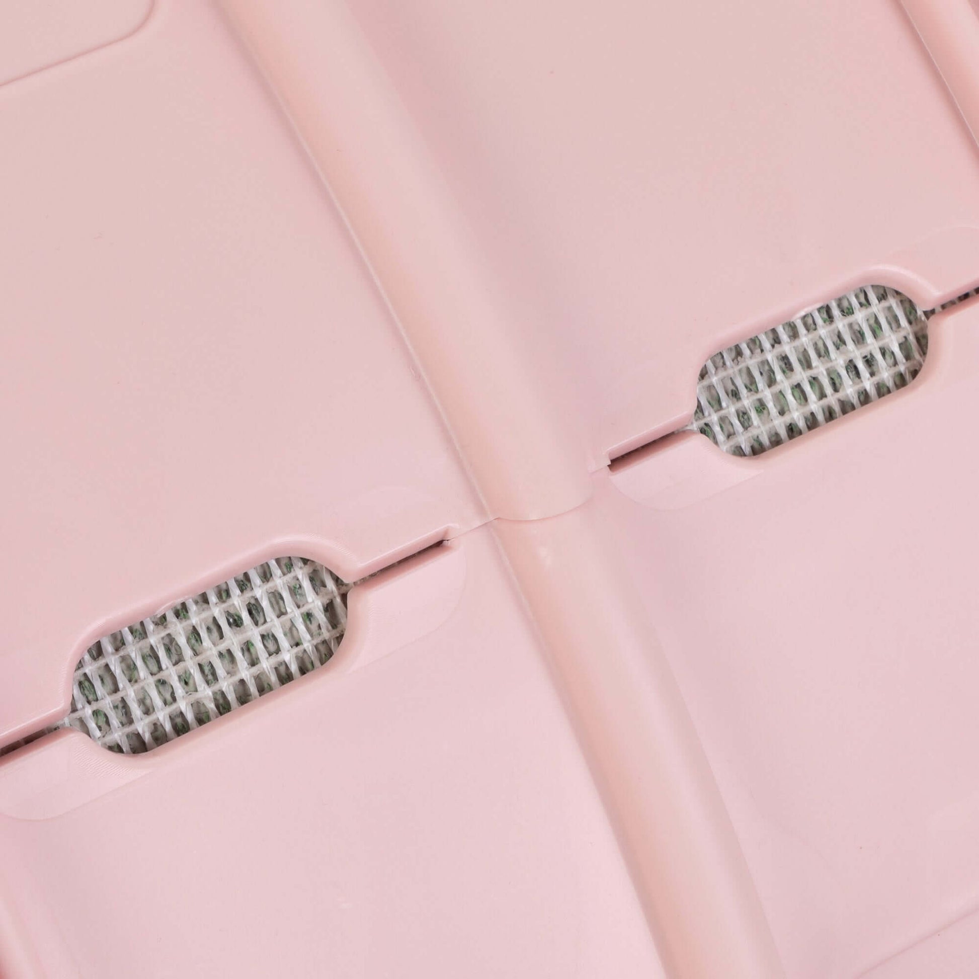 Close-up of the surface of a pink cat running wheel, showcasing ventilation holes for comfort and safety.