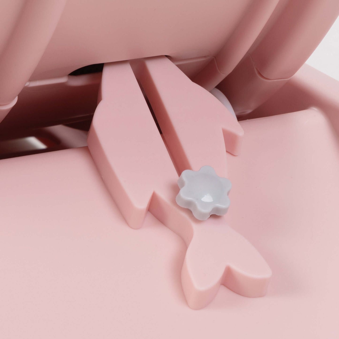 Close-up of a pink cat treadmill locking mechanism with flower-shaped button and fish-shaped components.