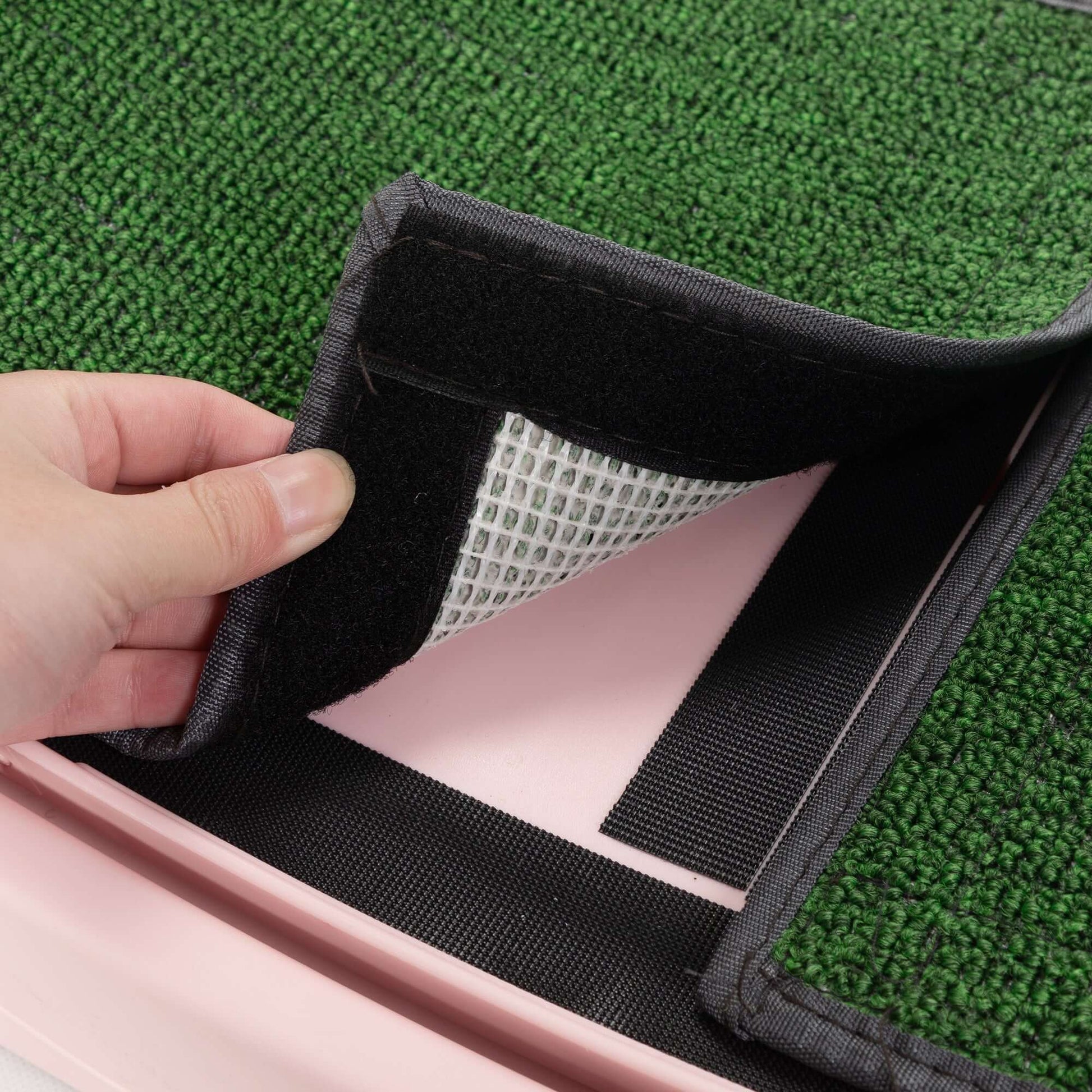 Hand showing the removable green mat of a cat running wheel, designed for easy cleaning and maintenance.