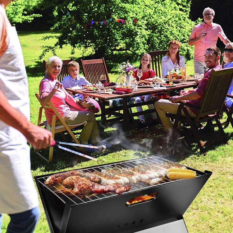 Portable BBQ grill with delicious food being prepared outdoors, surrounded by people enjoying a cheerful gathering.