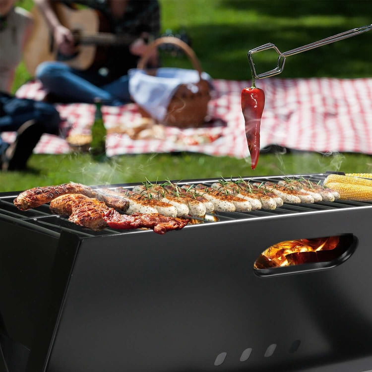 Portable BBQ grill with sizzling meat and fresh vegetables, perfect for camping or outdoor gatherings.