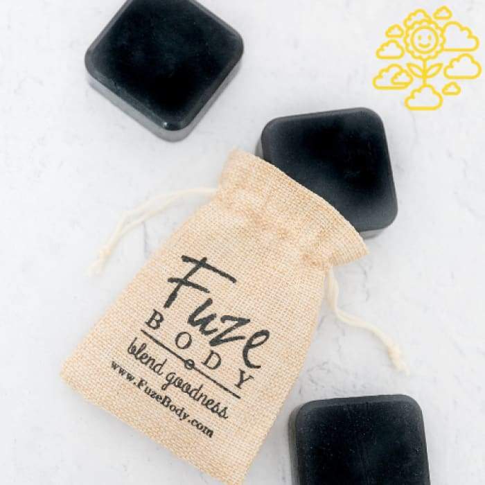 Joy Activated Charcoal Facial Soap in a Fuze Body sachet with three charcoal bars on a white surface.