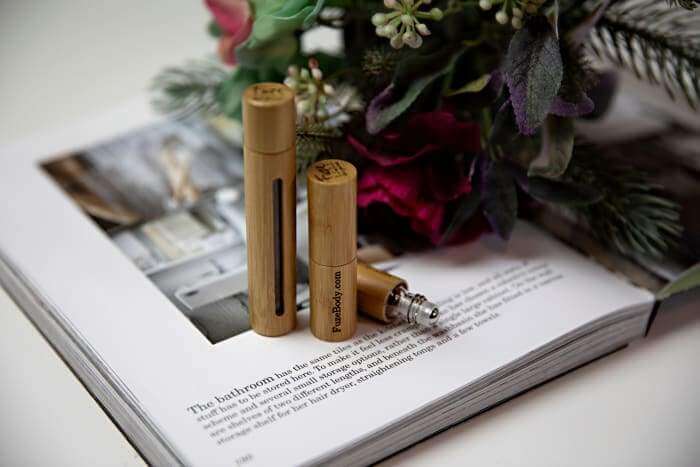 Wood roll-on essential oil bottles on an open book with flowers, showcasing natural wellness and relaxation.