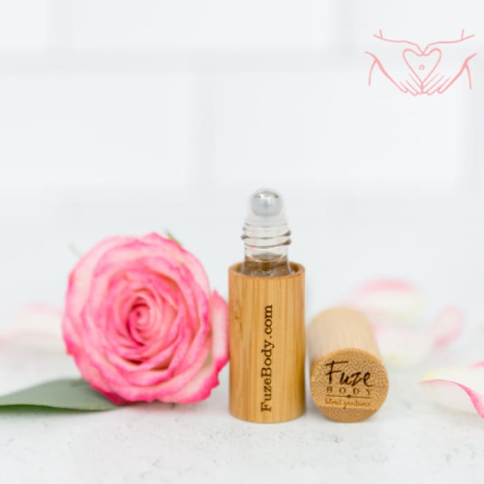 Wood roll-on essential oil bottle with pink rose petals, perfect for women's monthly comfort and cramp relief.