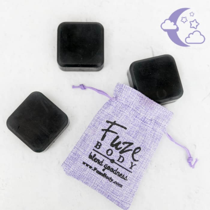 Sleep Activated Charcoal Facial Soap cubes beside a purple sachet by Fuze BODY, promoting skin nourishment and detox.