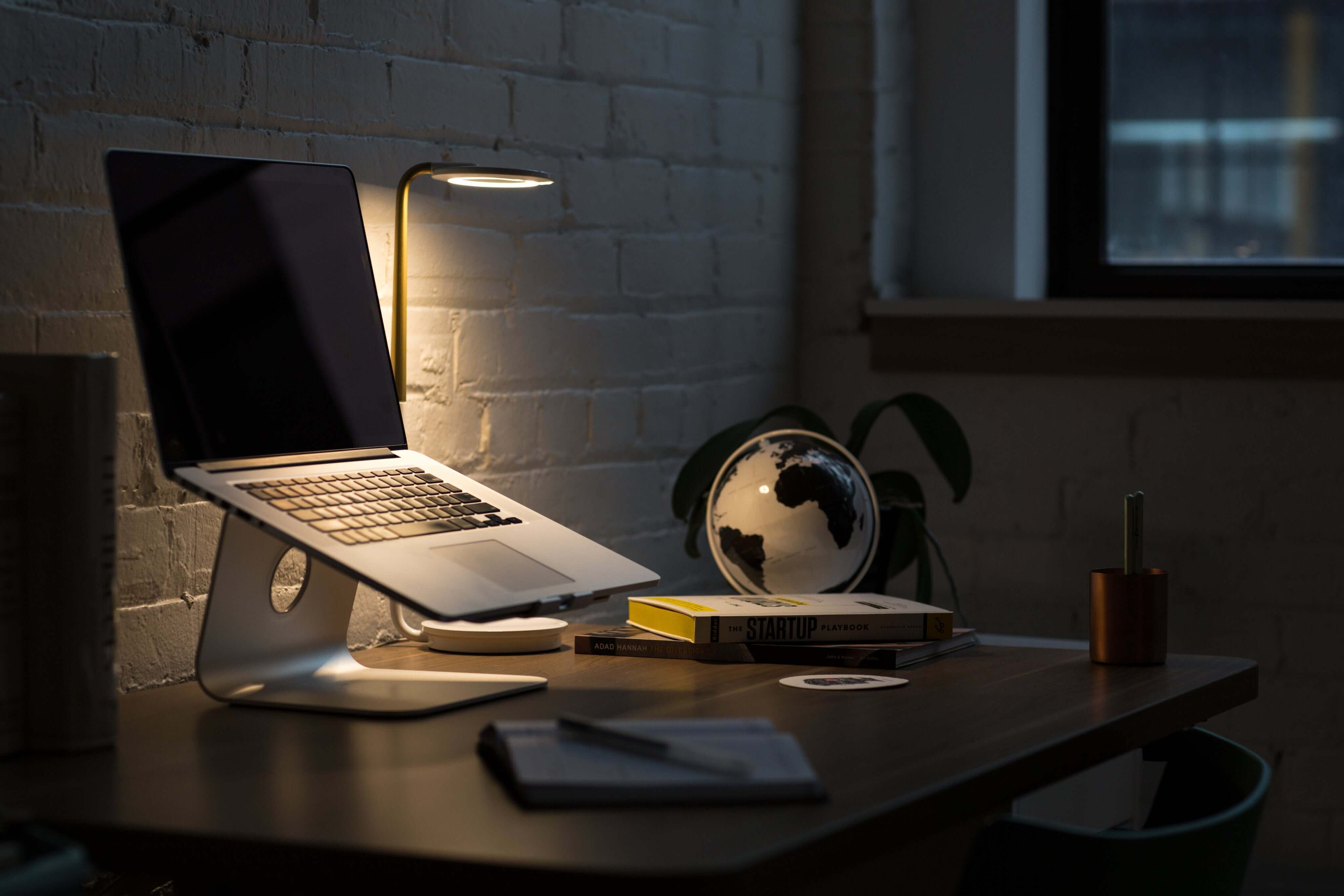 Cozy workspace featuring a laptop, desk lamp, globe, and books, perfect for productivity and inspiration.