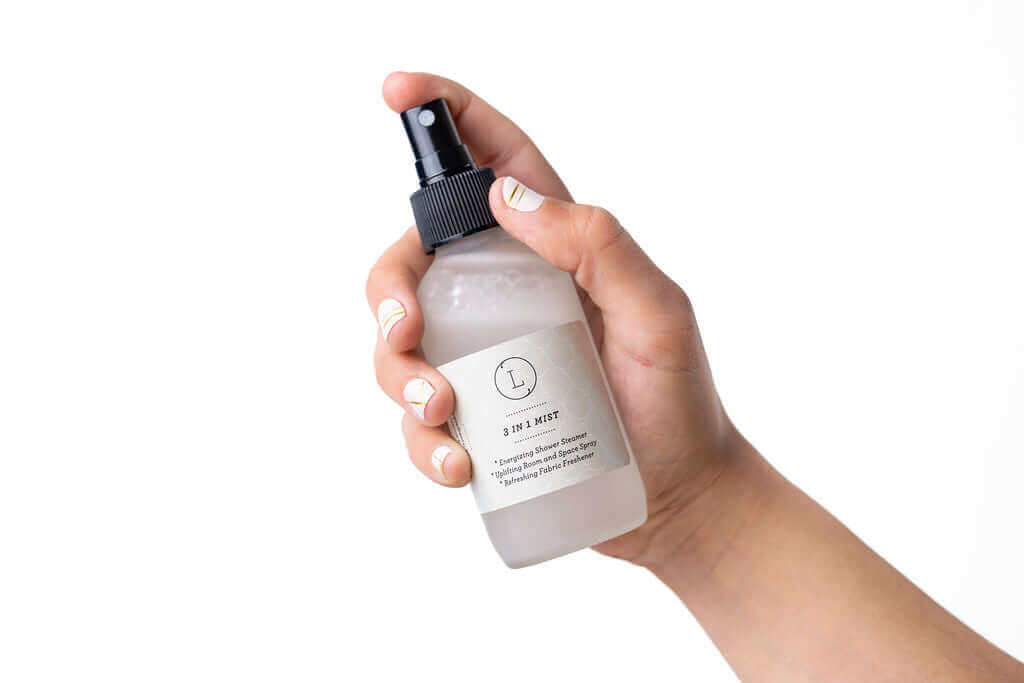 Hand holding a frosted glass bottle of natural body mist for relaxation and self-care.