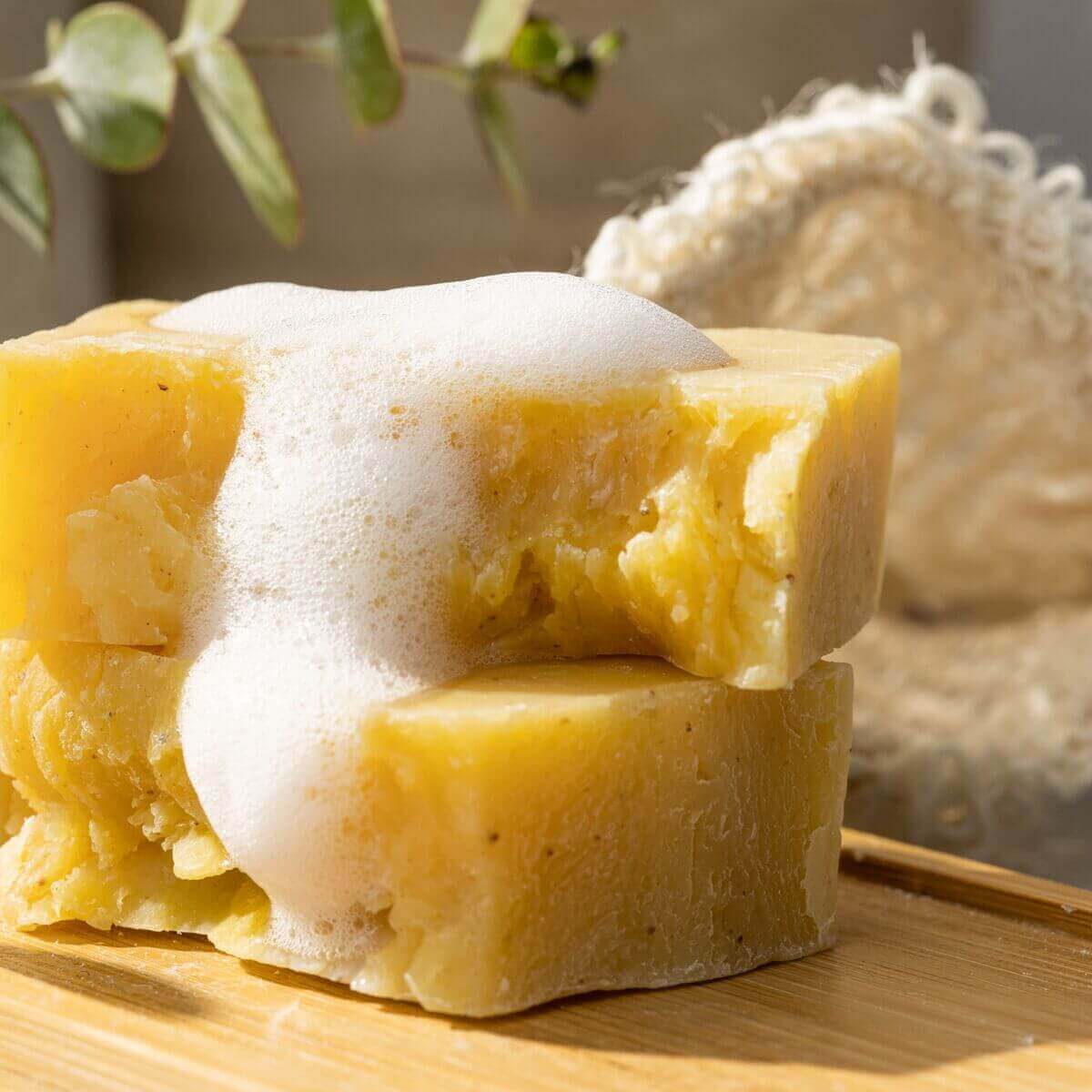 Handmade citrus soap bar with frothy bubbles, part of a luxurious natural bath and body gift box.