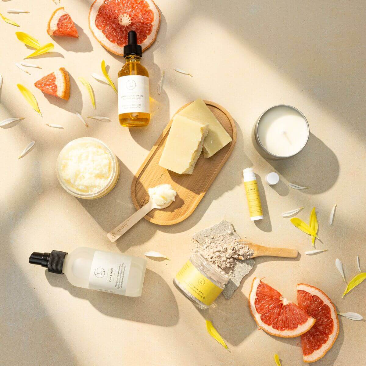 Handmade natural bath and body products arranged with grapefruit and petals, ideal for a care package or spa gift box.