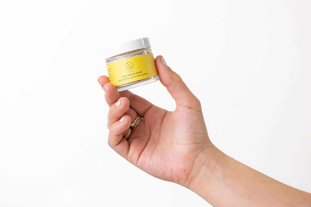 Hand holding a jar of natural body scrub with yellow label, perfect for spa gifts and self-care.