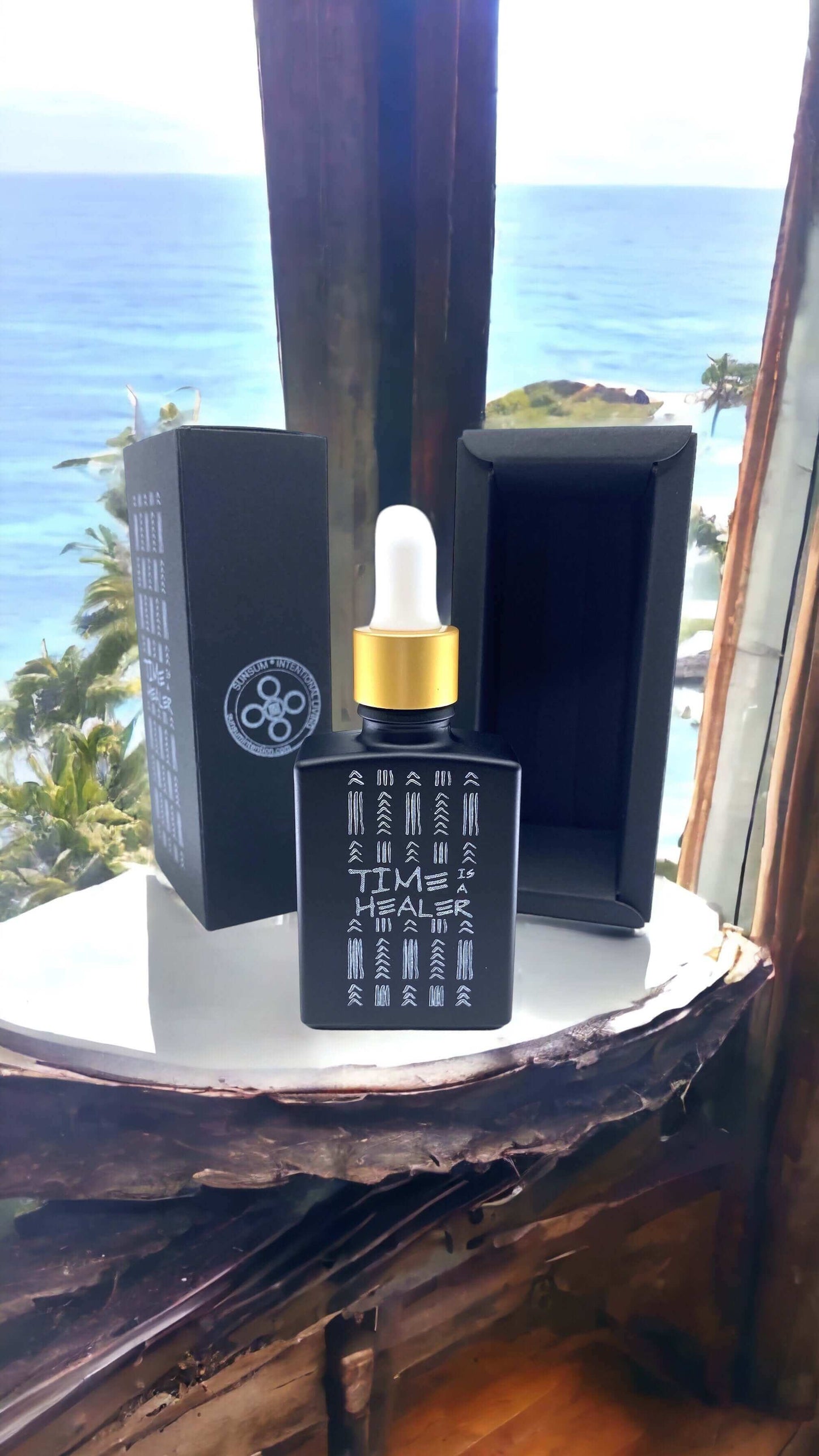 Time Is a Healer personal fragrance bottle and box by Sunsum against a scenic ocean view.