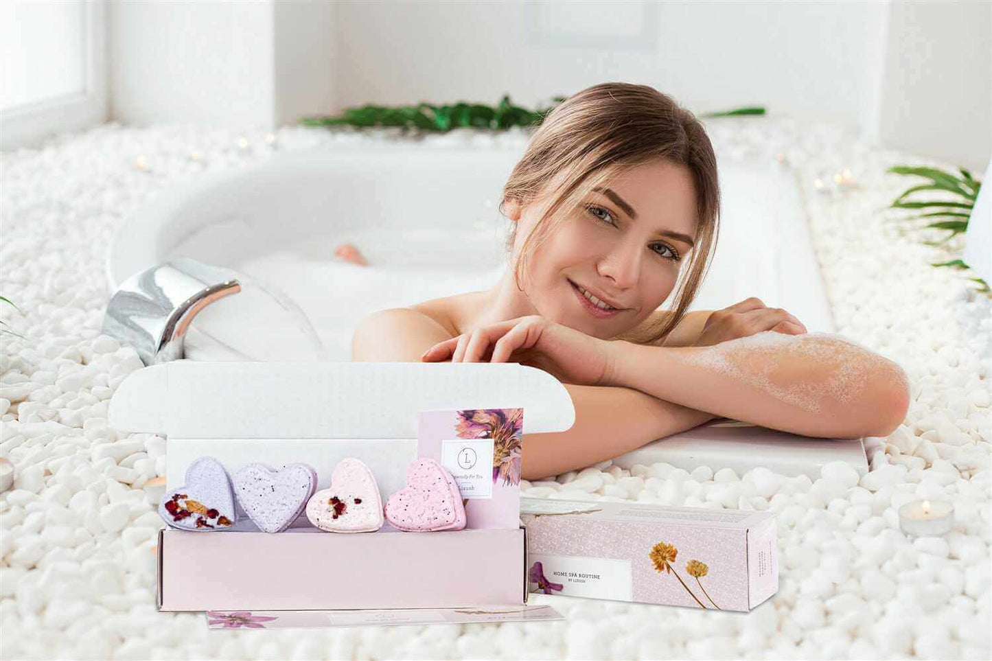 Heart-shaped shower steamers gift box with a woman relaxing in a bath surrounded by pebbles.