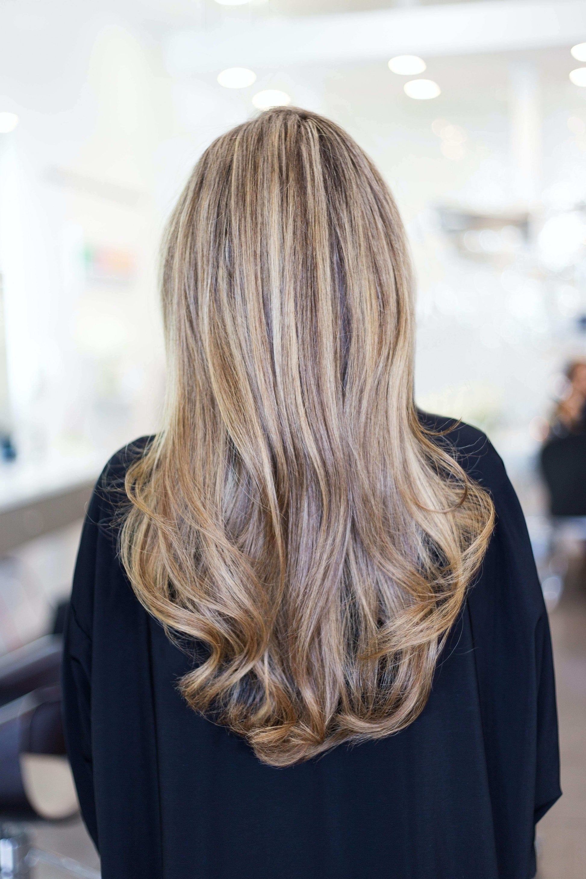 Long, wavy blonde hair styled beautifully in a salon setting, showcasing healthy, voluminous locks.